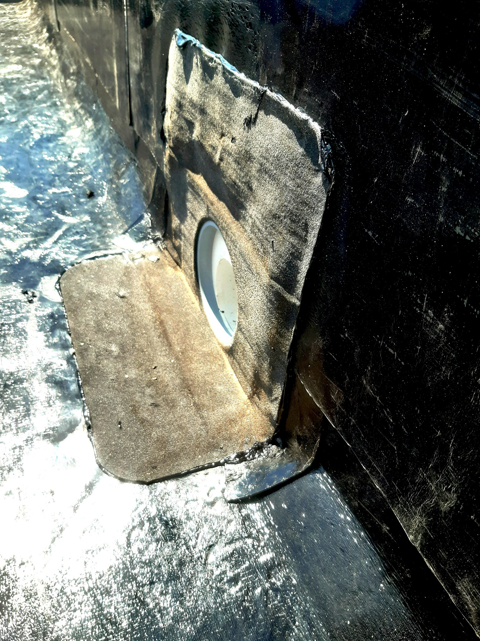 Szczegółowe ujęcie uszczelnienia przejścia rury przez hydroizolację dachu płaskiego, z widocznymi warstwami papy i obróbkami blacharskimi.