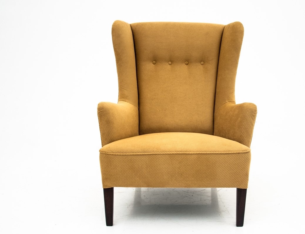 Żółty fotel typu uszak z trzema guzikami na oparciu, ciemne drewniane nogi, na białym tle.