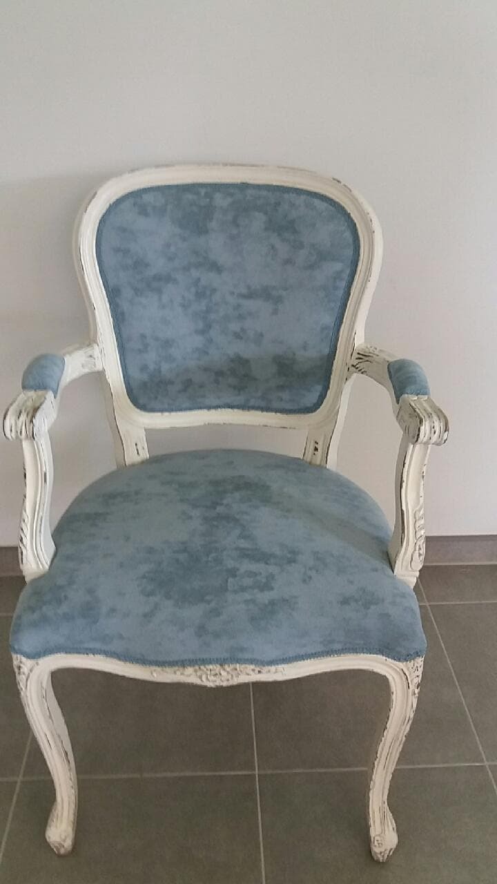 Odrestaurowany fotel w stylu Ludwika z białą ramą i błękitną, pluszową tapicerką, widoczne przetarcia na ramie.