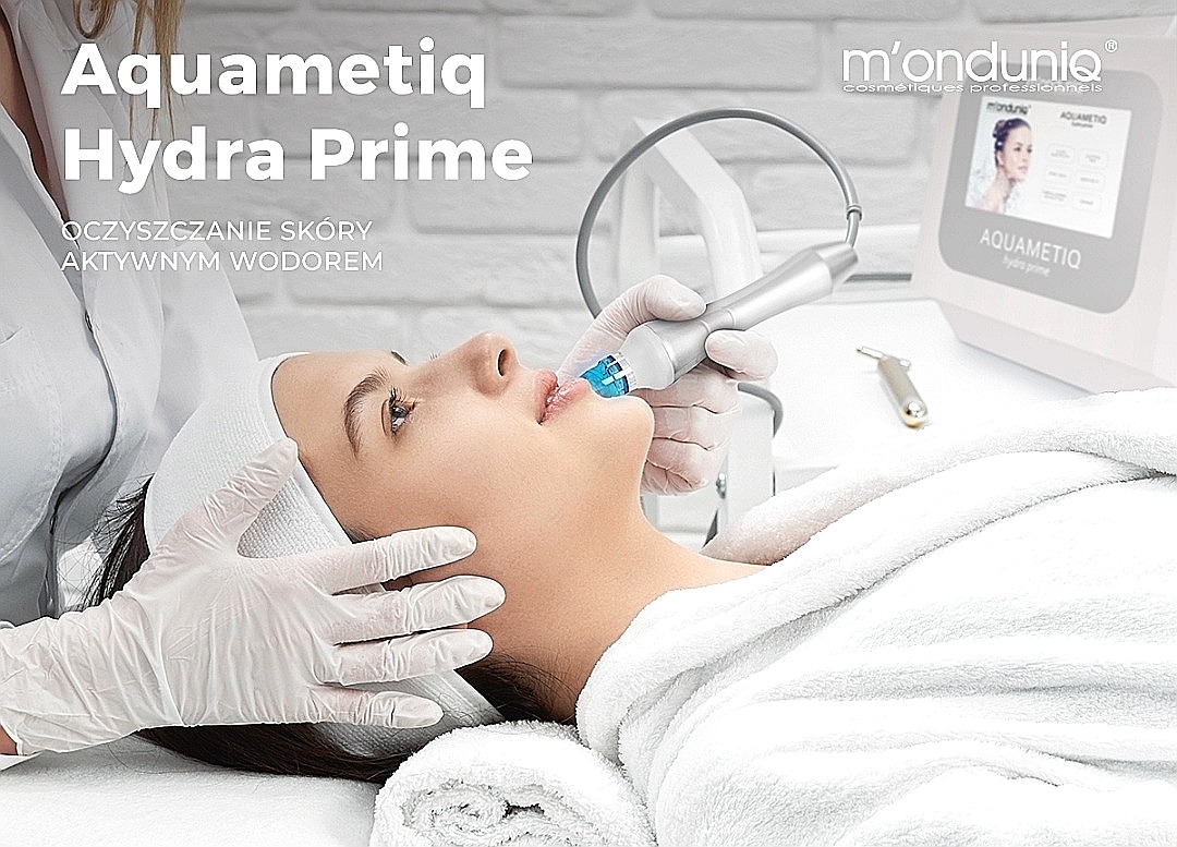Kobieta w białym szlafroku poddawana zabiegowi oczyszczania skóry twarzy aktywnym wodorem przy użyciu urządzenia Aquametiq Hydra Prime, widoczny ekran urządzenia z logo m'ondunio.