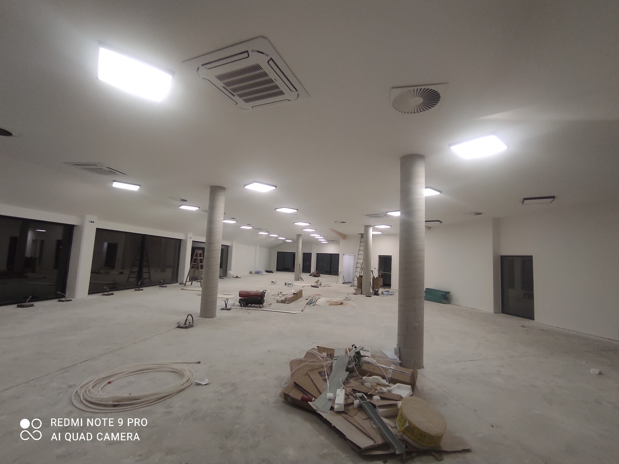 Wnętrze w trakcie montażu instalacji: widoczne kable, narzędzia, puszki instalacyjne, oświetlenie sufitowe, klimatyzacja i wentylacja.