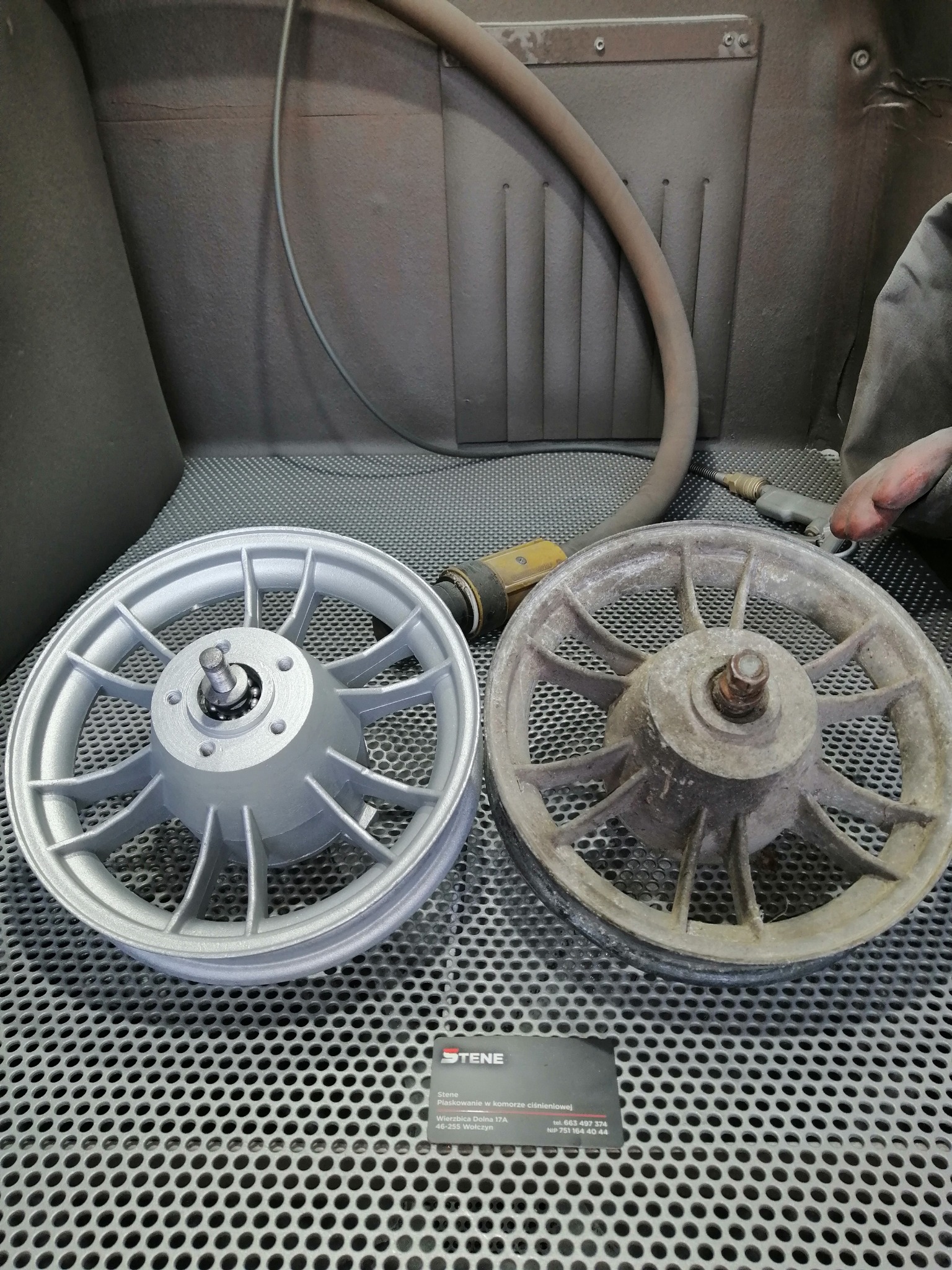 Porównanie felgi przed i po renowacji: surowa, skorodowana felga obok odnowionej, pomalowanej na srebrno, na tle komory roboczej z widocznymi narzędziami i wizytówką firmy.