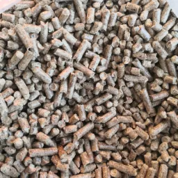 Jasnobrązowy pellet drzewny w przezroczystym worku, widok z góry, nierównomierne oświetlenie.