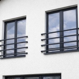 FilART - Construction Damian Filar - Dwa okna z czarnymi, minimalistycznymi kratami na białej, teksturowanej elewacji budynku. Widoczne odbicie nieba w szybach.