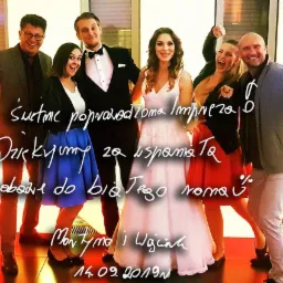 Uśmiechnięta grupa osób, prawdopodobnie wykonawców muzycznych i gości, pozuje do zdjęcia na tle jasnej ściany podczas imprezy. Na pierwszym planie widoczny biały napis z podziękowaniem za udaną...