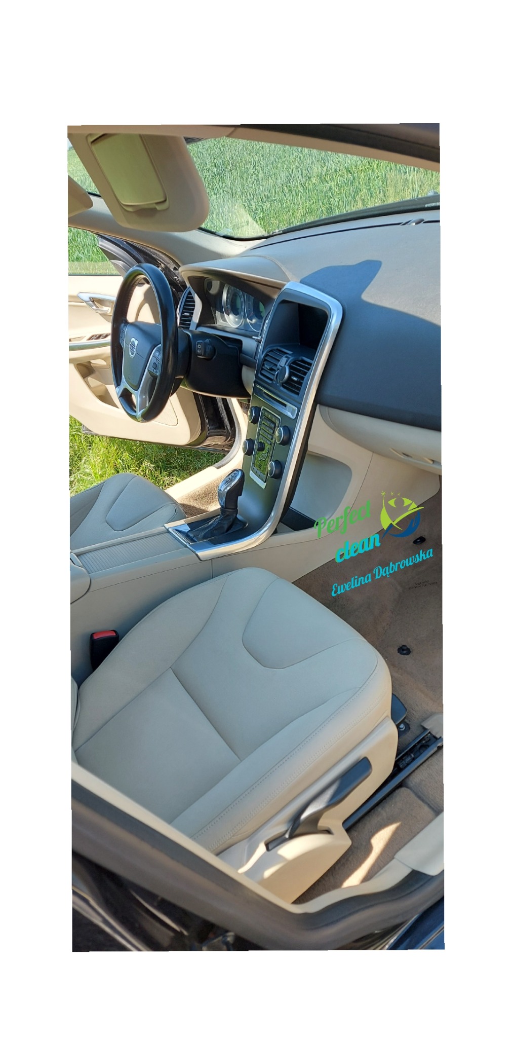 Wnętrze samochodu Volvo po czyszczeniu, beżowa skórzana tapicerka foteli i deski rozdzielczej, widoczny fragment szyby i zielona trawa w tle, logo firmy Perfect Clean nałożone na zdjęcie.