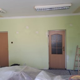 Darlbud Mateusz Dul - Pokój w trakcie szpachlowania ścian, z widocznymi łatami szpachli, zabezpieczoną folią podłogą, drewnianą drabiną i dwoma drzwiami.