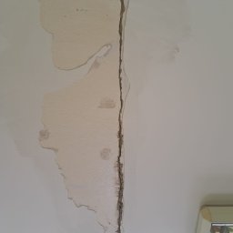 Darlbud Mateusz Dul - Pęknięcie na suficie z widocznymi śladami po naprawie, częściowo pokryte masą szpachlową, ukazujące etap prac remontowych.