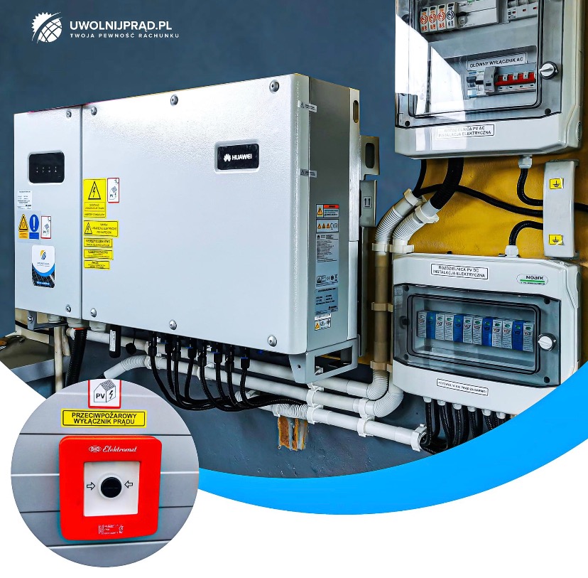 Instalacja fotowoltaiczna: falownik Huawei, rozdzielnice elektryczne PV AC i DC, przeciwpożarowy wyłącznik prądu z czerwonym przyciskiem, białe rury instalacyjne.