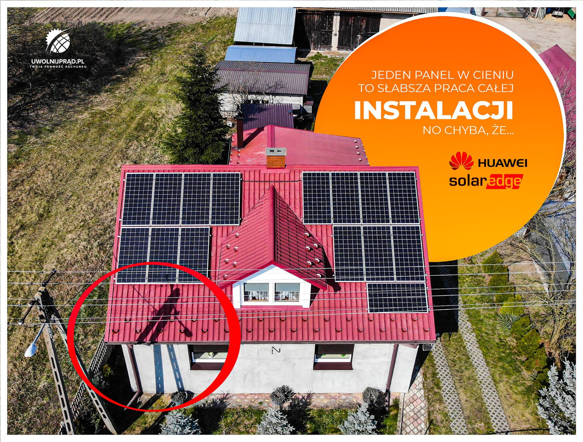 Widok z góry na dom z czerwonym dachem pokrytym panelami słonecznymi, z widocznym cieniem osoby na dachu, obok pomarańczowe logo firmy zajmującej się instalacją paneli słonecznych.