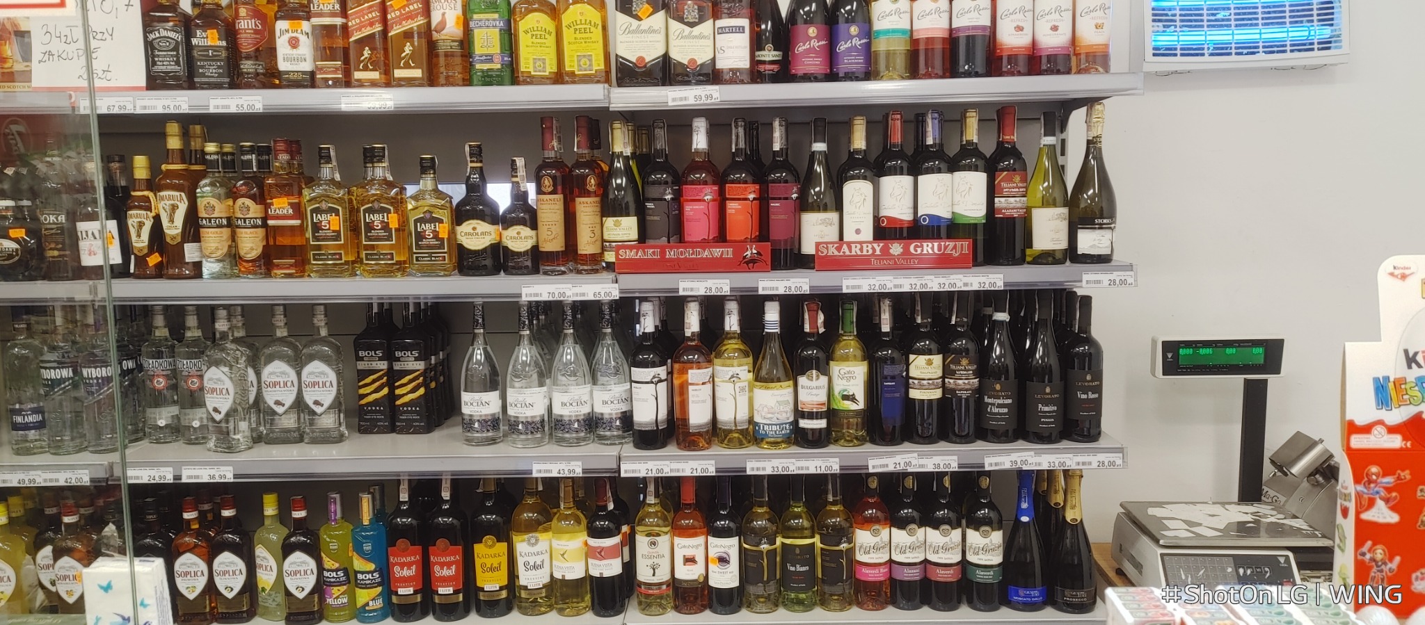 Półki w sklepie w Żorach wypełnione różnorodnymi butelkami alkoholi, w tym wódki, wina i whisky, z widocznymi cenami i etykietami producentów.