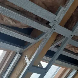 Szkielet metalowy pod płytę karton gips na poddaszu z widoczną izolacją z wełny mineralnej, widok od dołu.