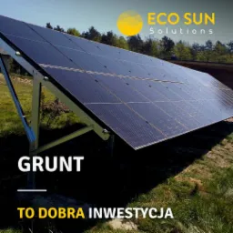 Panel słoneczny zamontowany na gruncie z widocznym logo firmy Eco Sun Solutions, otoczony zieloną trawą i drzewami w tle.