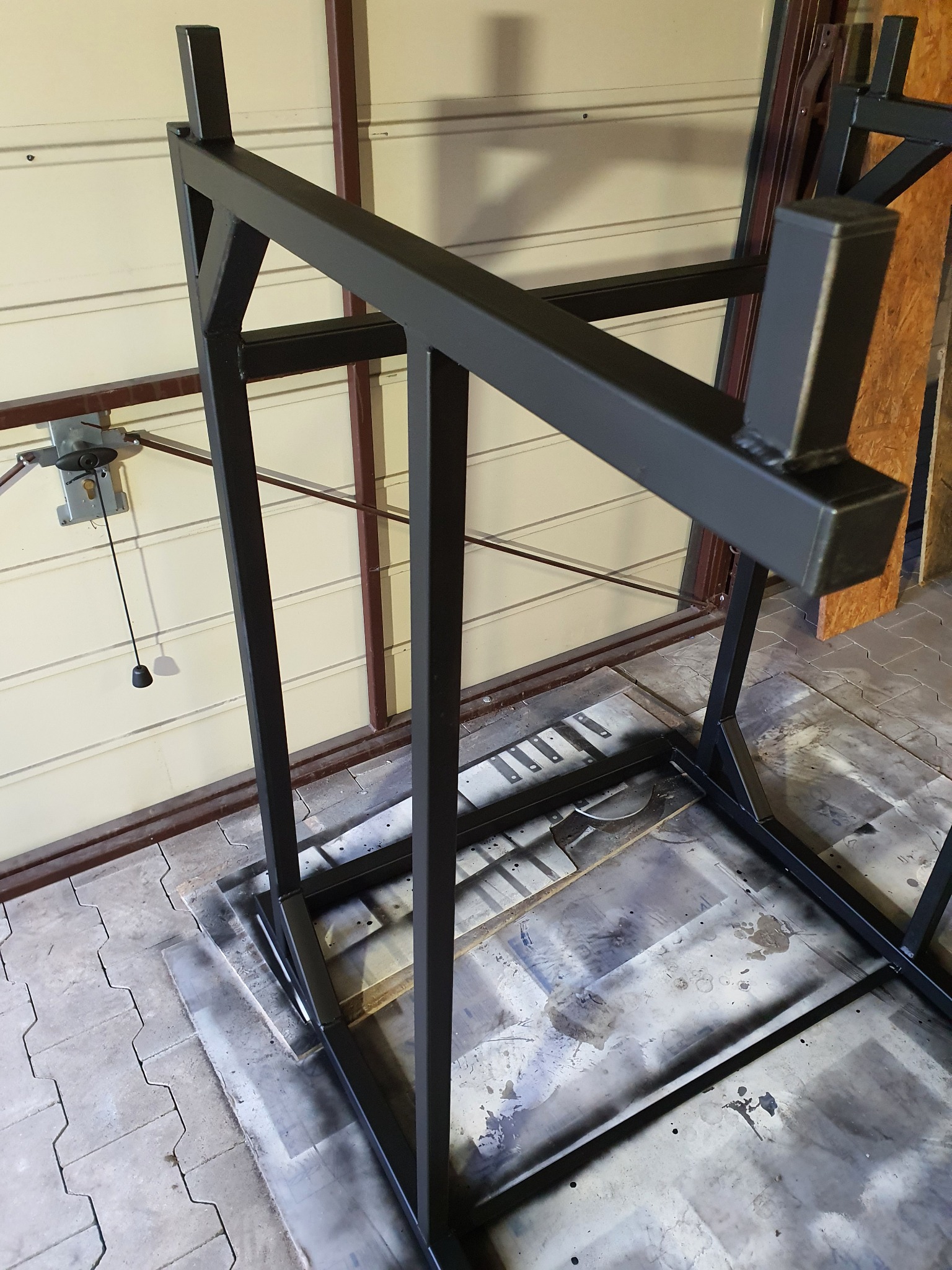 Konstrukcja metalowa spawana z profili zamkniętych, pomalowana na czarno, wykonana przez spawacza z Poznania, widoczna w warsztacie.