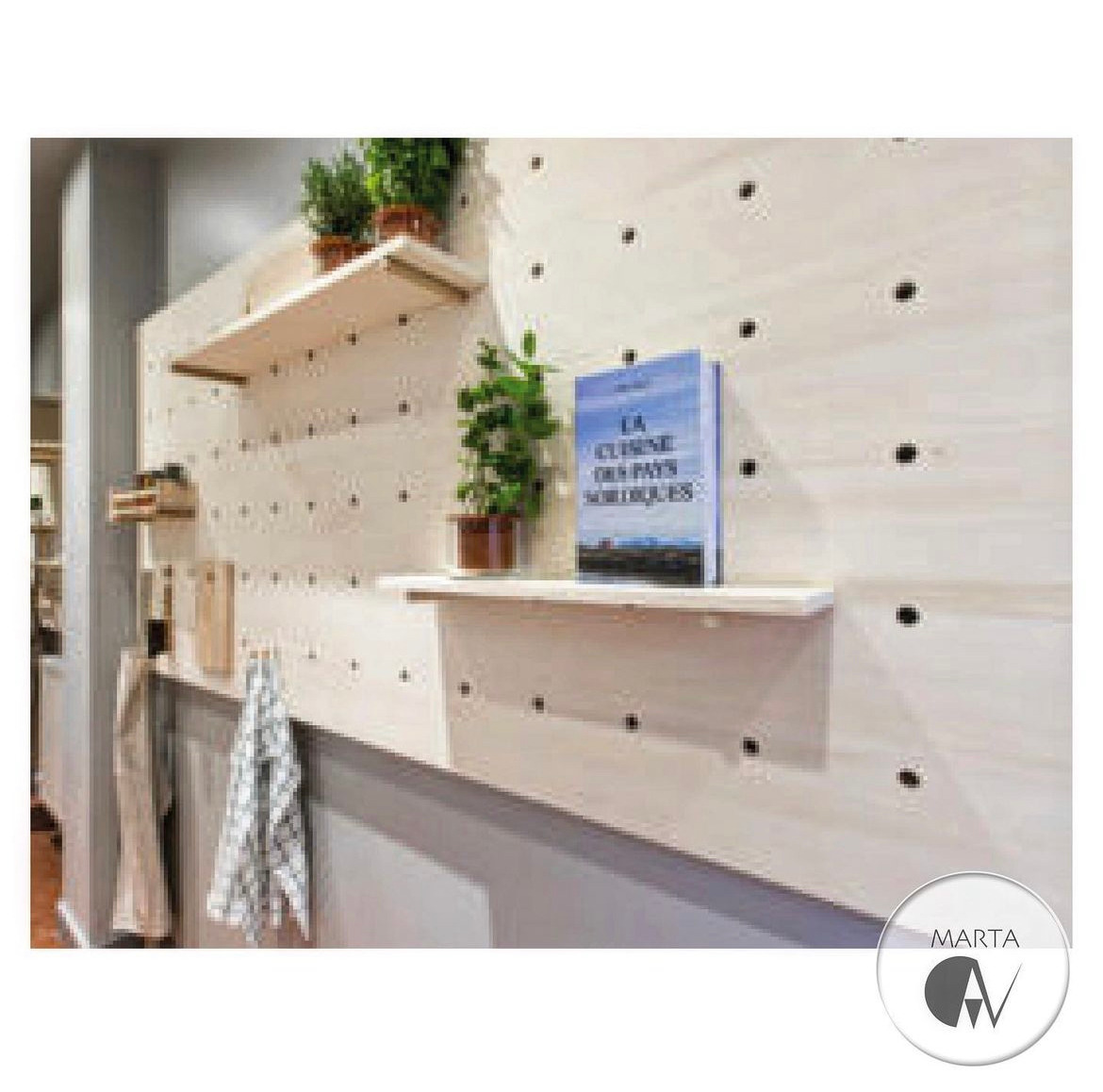 Drewniana ściana z otworami, na której zamontowano półki z roślinami w doniczkach i książką kucharską. Widoczny fragment przedpokoju z wieszakami i ręcznikiem. Minimalistyczny styl.