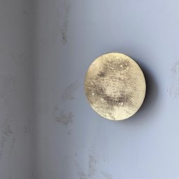 MD CONCEPT - Dekoracyjna, złota rozeta na szarej ścianie z delikatną fakturą. Okrągła ozdoba z efektem przetarć, umieszczona na styku dwóch ścian, tworzy unikalny akcent wnętrza.