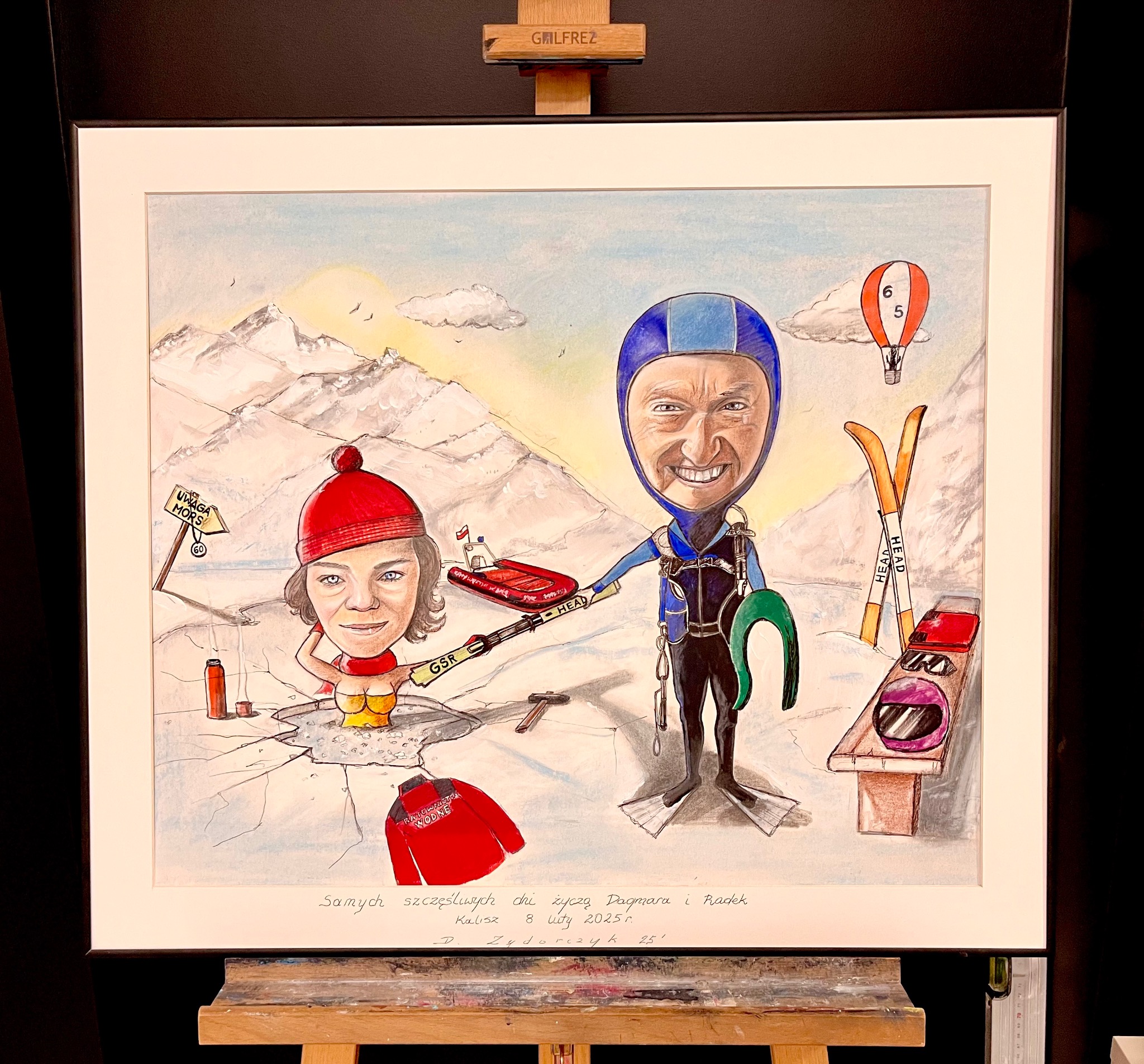 Oprawiony rysunek przedstawia karykaturalną scenę zimową z nurkiem i morsującą kobietą, z górami w tle, podpisany życzeniami i datą 8 luty 2025.