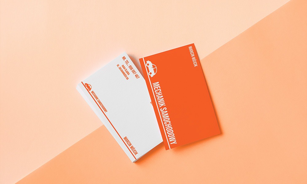 Dwie wizytówki mechanika samochodowego w pomarańczowo-białej kolorystyce, ułożone pod kątem na dwukolorowym tle w odcieniach brzoskwini. Na wizytówkach widoczne dane kontaktowe oraz grafika samochodu.