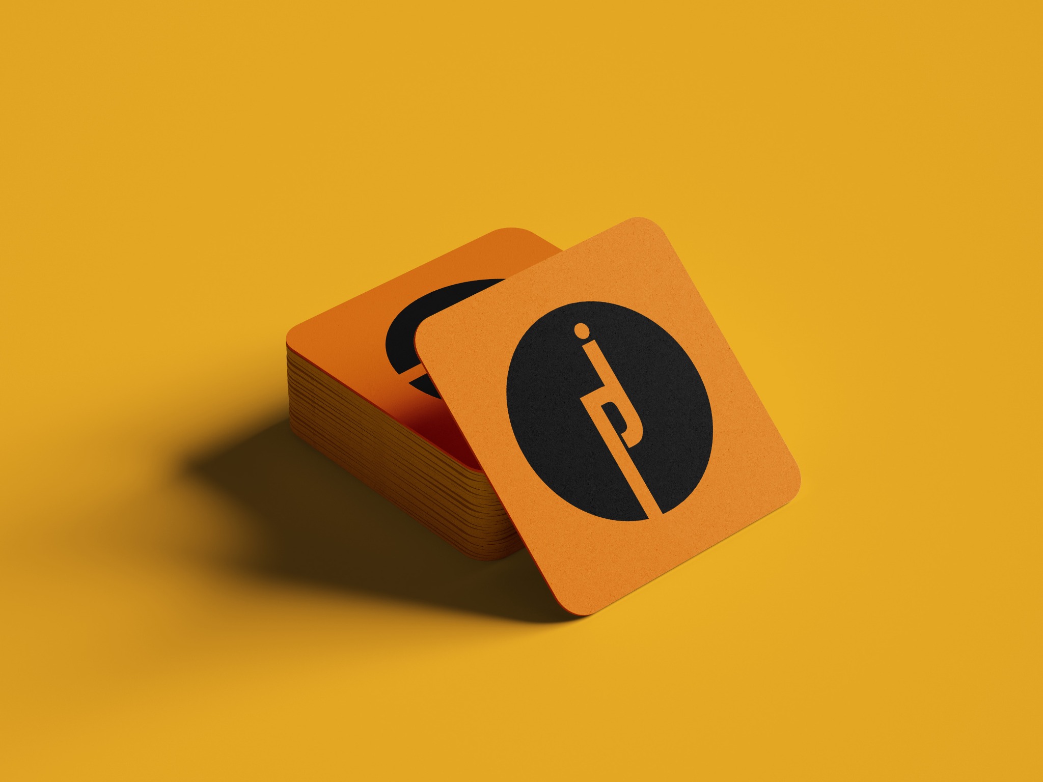 Stos pomarańczowych, kwadratowych wizytówek z czarnym logo na żółtym tle, oświetlonych z lewej strony.