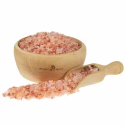 Drewniana miseczka wypełniona różową solą himalajską, z drewnianą łyżeczką obok, na której również znajduje się sól; widoczne logo 'gorzko słodko' na miseczce.