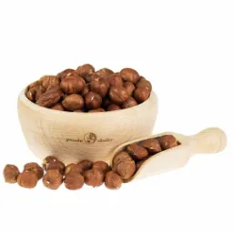 Drewniana miseczka wypełniona orzechami laskowymi, z napisem 'gorzko słodko', obok leży drewniana łyżeczka z orzechami, całość na białym tle.