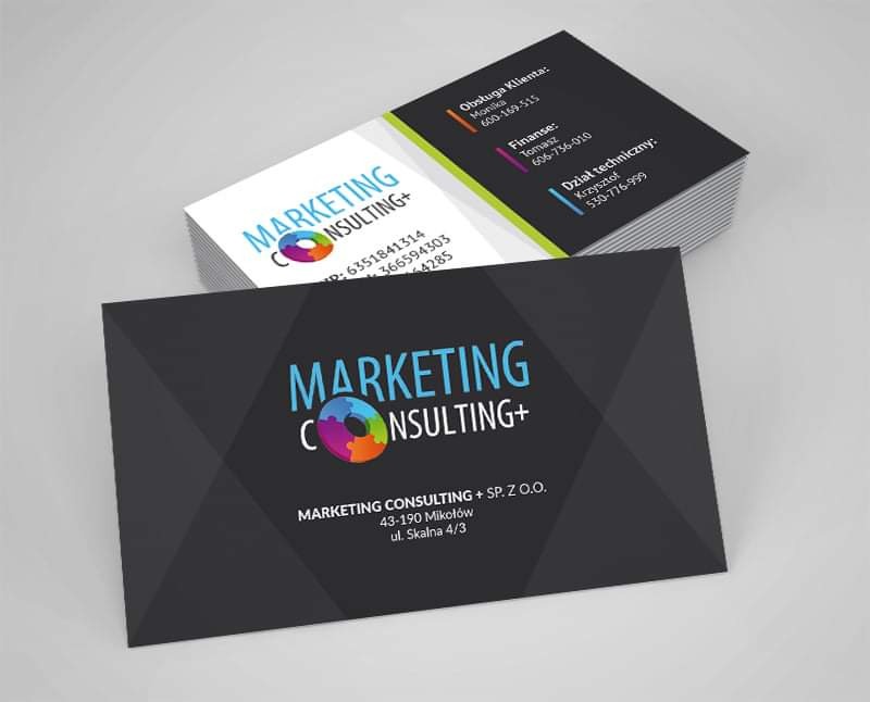 Stos wizytówek firmy Marketing Consulting+ z ciemnoszarym tłem, logo z kolorowym okręgiem i danymi kontaktowymi, ułożonych na jasnym tle.