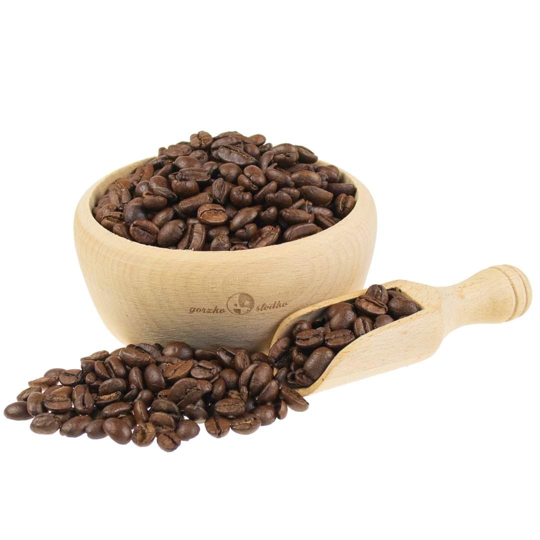 Ziarna kawy w drewnianej miseczce i nabierce, z napisem 'gorzko słodko', na białym tle.