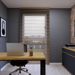 MSPROJEKT Michał Świerczek - Biuro w szarościach z drewnianym biurkiem i ceglaną ścianą. Na blacie laptop, organizer z przyborami. Żaluzje drewniane w oknie. Minimalistyczny design.