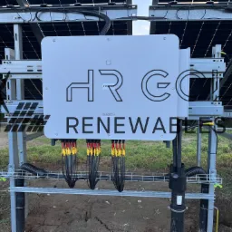 Inwerter solarny Sungrow HRG Renewables zamontowany na metalowej konstrukcji, z widocznymi kablami i panelami słonecznymi w tle.