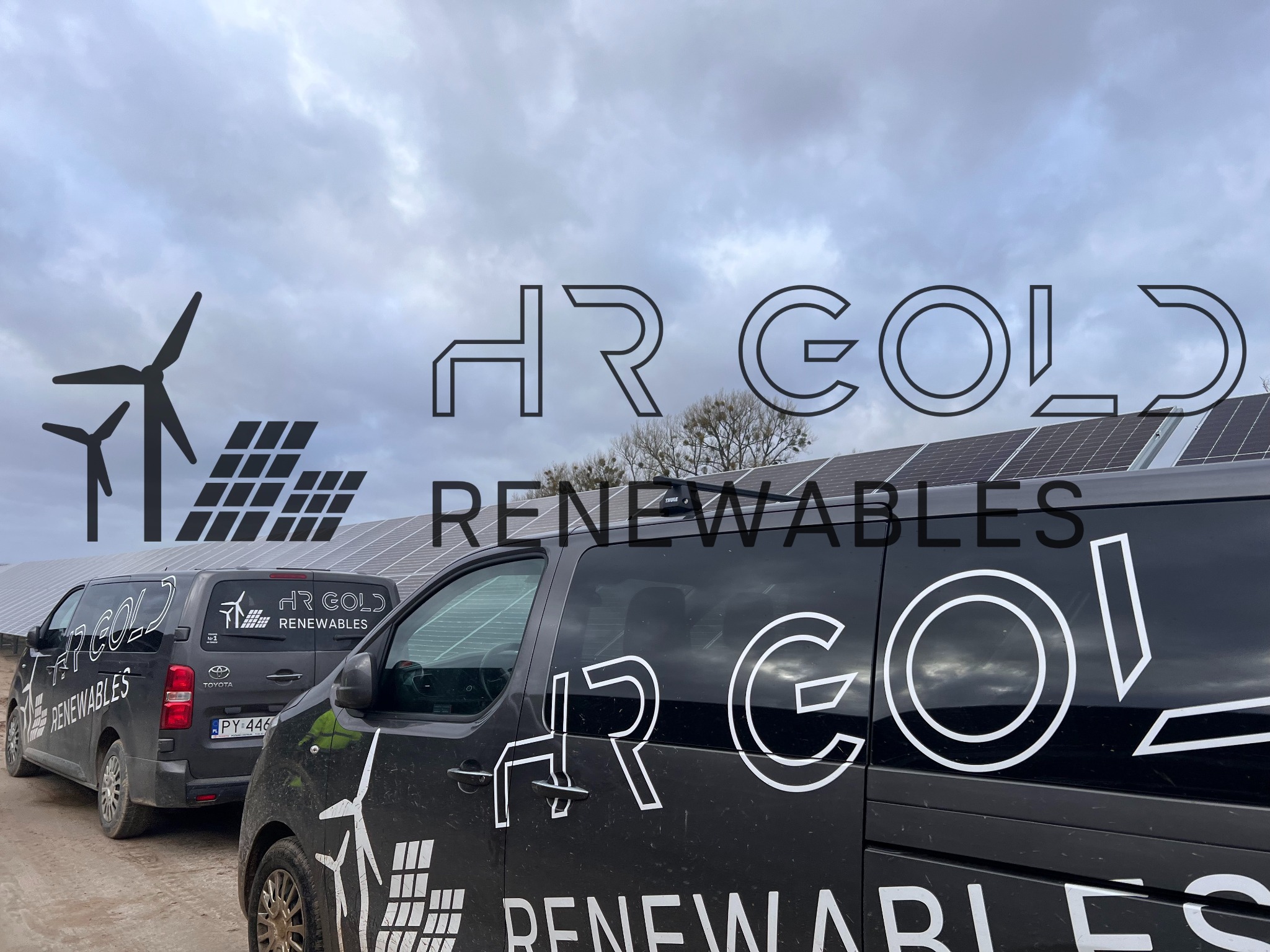 Dwa czarne samochody firmy HR Gold Renewables z Poznania zaparkowane przed farmą paneli słonecznych, z widocznym logo firmy z wiatrakiem i panelem słonecznym.
