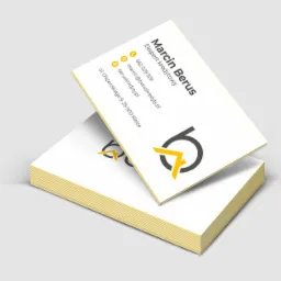 Stos wizytówek z danymi kontaktowymi eksperta kredytowego Marcina Berusa, logo w kolorach szarym i żółtym, widok z góry pod kątem.