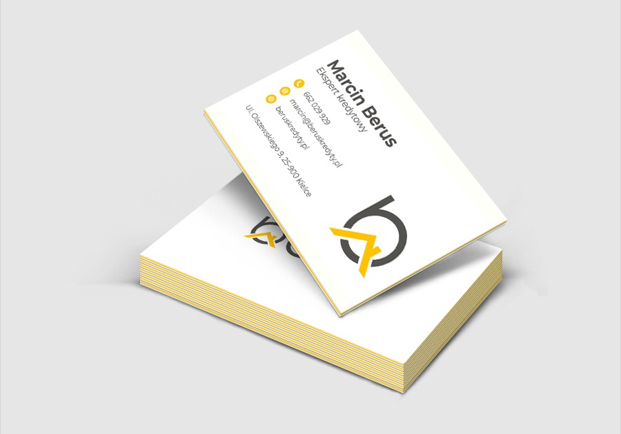 Stos wizytówek z danymi kontaktowymi eksperta kredytowego Marcina Berusa, logo w kolorach szarym i żółtym, widok z góry pod kątem.