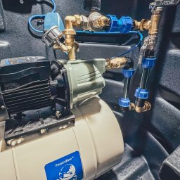 PROWIERT SPÓŁKA Z OGRANICZONĄ ODPOWIEDZIALNOŚCIĄ - Kompletna instalacja pompy głębinowej w studni z osprzętem: zbiornik hydroforowy, automat SAFEMATIC, zawory i rury. Widok z góry, oświetlenie techniczne.