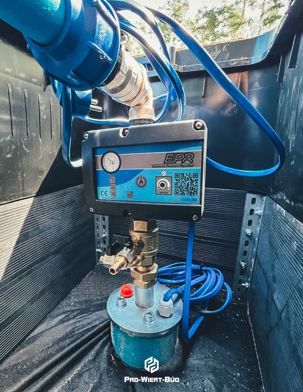 Elektroniczny regulator ciśnienia EPR w studzience z niebieskimi przewodami, widoczny manometr i QR kod producenta Coelbo.