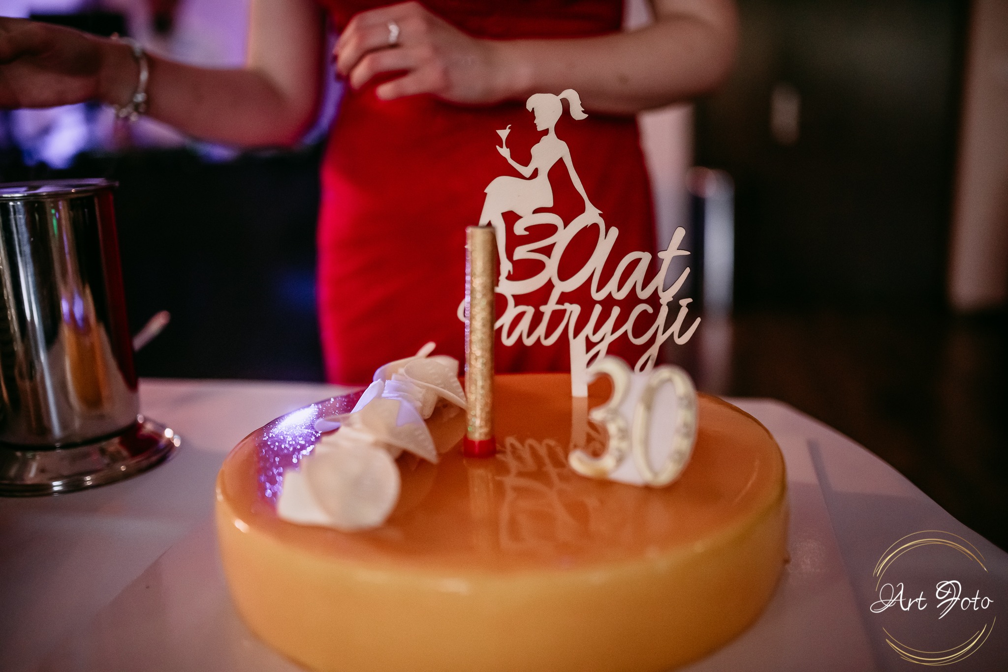 Tort na 30 urodziny Patrycji, dekorowany topperem z sylwetką kobiety z drinkiem. W tle postać w czerwonej sukience i srebrny shaker.