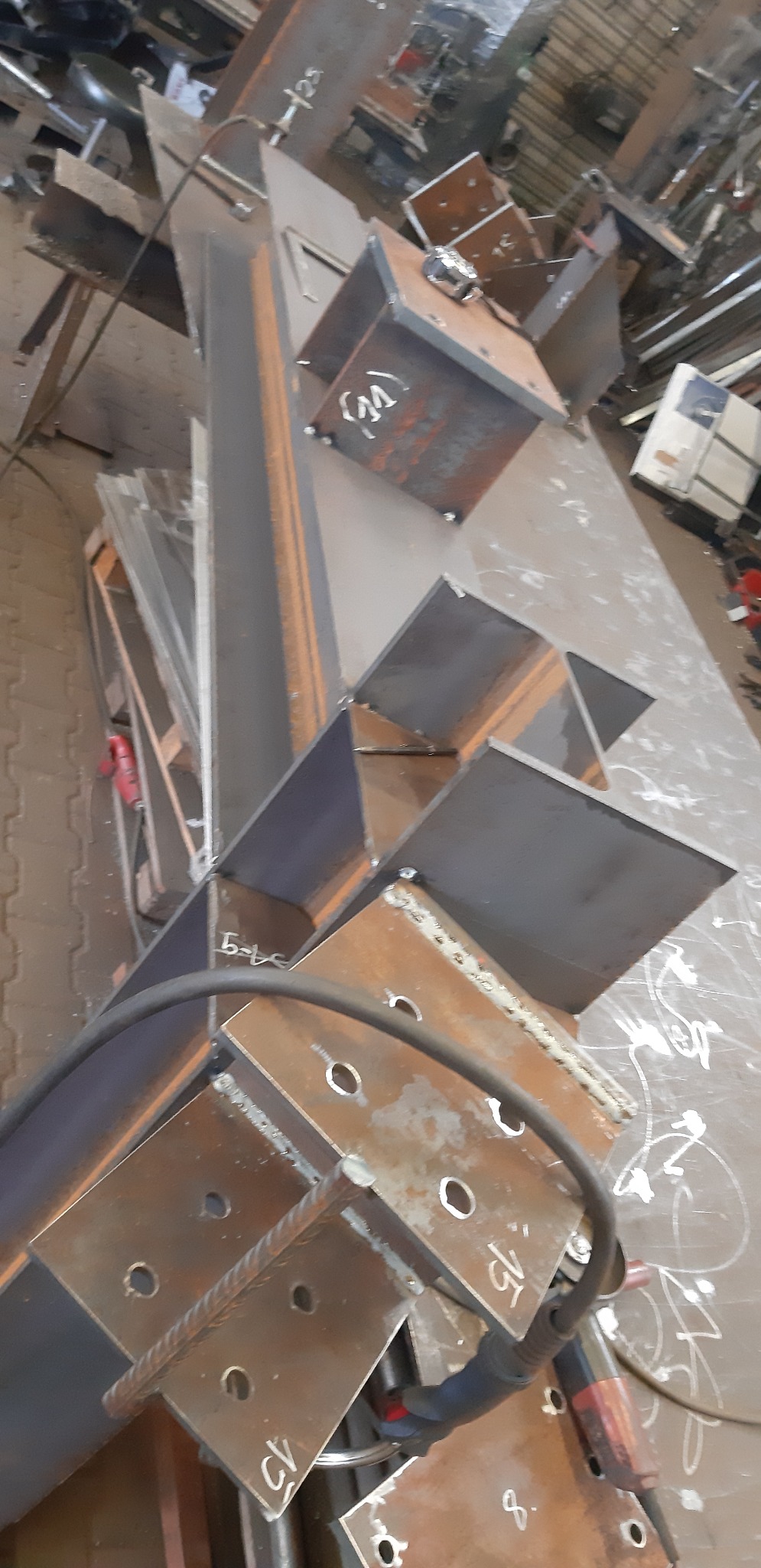 Konstrukcja schodów metalowych w trakcie budowy w warsztacie, widoczne elementy spawane i otwory montażowe.