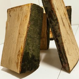 KMMOBILI Krystian Miętka - Kilkakrotnie pocięte, prostokątne kawałki drewna z korą, ustawione pionowo na białym tle.