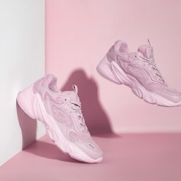 PFH KATARZYNA SOŁTYSIAK - Stylizowana fotografia produktowa: dwa identyczne, różowe sneakersy unoszą się w przestrzeni na tle różowo-białego, minimalistycznego tła. Cienie dodają głębi.