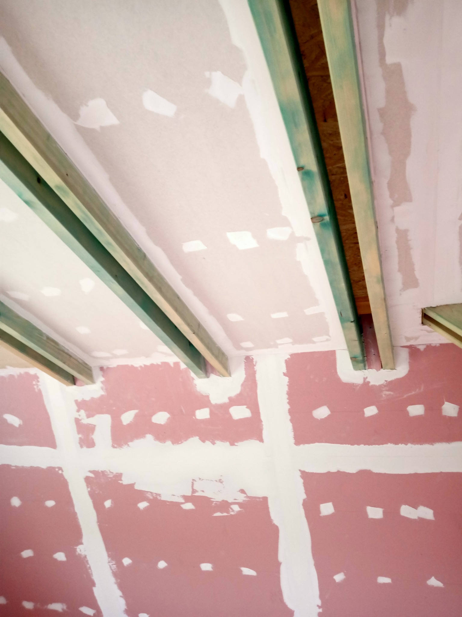 Ściana i sufit w trakcie przygotowywania do gładzi, widoczne profile drewniane i płyty kartonowo-gipsowe z widocznymi łączeniami.