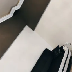 Pok&oacute;j po remoncie: kontrastowe połączenie brązowej i kremowej ściany, dekoracyjny gzyms sufitowy, narożnik z czarno-białą tapicerką i ozdobnymi poduszkami.