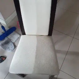 Krzesełko z tapicerką, widoczna różnica w czystości między wyczyszczoną a nie wyczyszczoną częścią siedziska, obok mop i ścierka.