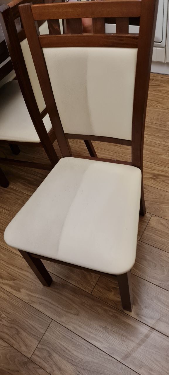 Krzesło z drewnianą ramą i jasnym obiciem, ukazujące efekt czyszczenia tapicerki - widoczna różnica między obszarem wyczyszczonym a zabrudzonym.