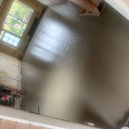 PROFESTON - Świeżo wylana, mokra wylewka samopoziomująca w pomieszczeniu w trakcie remontu, widoczne narzędzia i laser krzyżowy