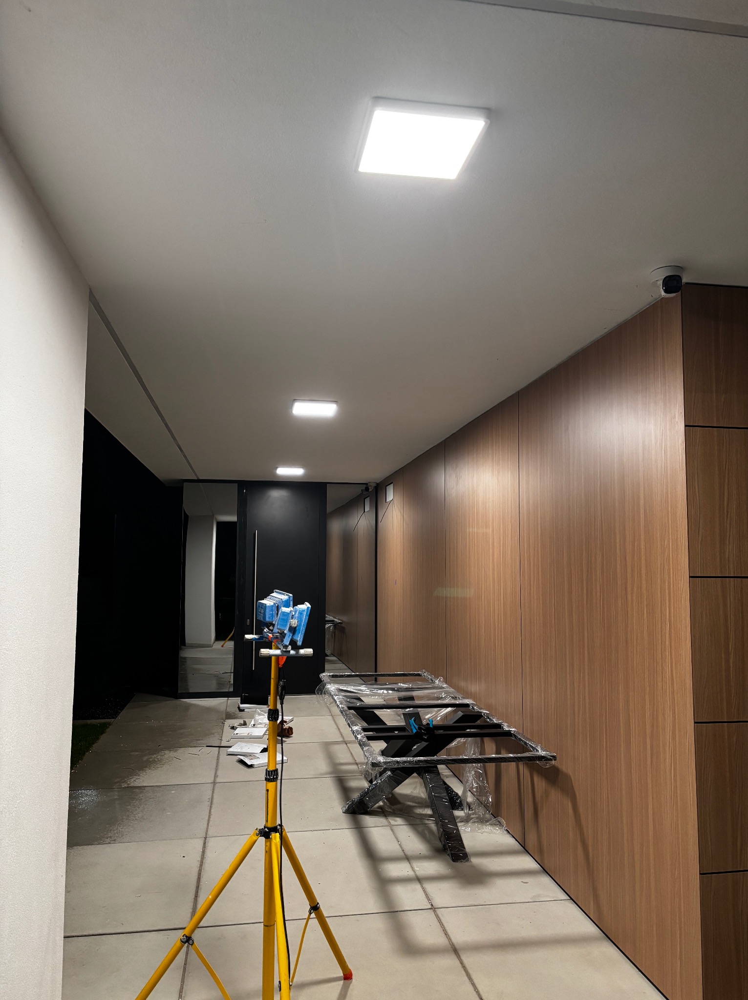 Wnętrze z zamontowanym oświetleniem sufitowym LED. Widoczna lampa na statywie oświetleniowym. Na ścianie zamontowany monitoring. Nowoczesny design.