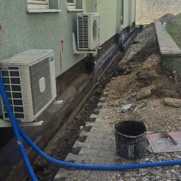 MAR MAX - Przygotowanie do izolacji fundamentów budynku z klimatyzatorami na elewacji, widoczny wykop, betonowe bloczki, niebieski karbowany wąż i wiadro.
