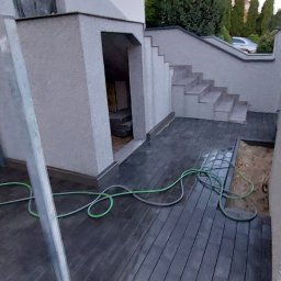 Mój Market Avetik Vanetsyan - Ułożona ciemna kostka brukowa na podwórku z widocznym wejściem do piwnicy, schodami i fragmentem węża ogrodowego.