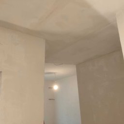 Mój Market Avetik Vanetsyan - Ściany i sufit świeżo po nałożeniu gładzi gipsowej, widoczne nierówności i ślady szpachlowania, przygotowane do malowania.