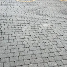 Ułożona szara kostka brukowa z żółtymi obrzeżami, widok z góry pod kątem.