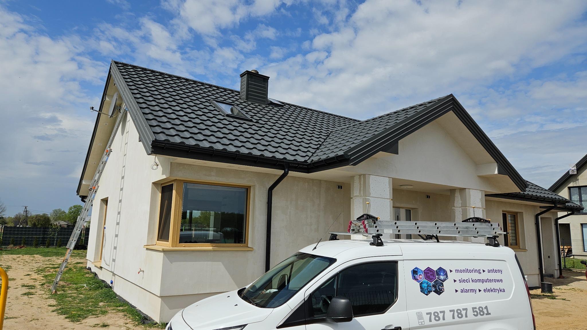 Nowoczesny dom z zamontowaną anteną satelitarną, widoczna drabina oparta o ścianę i firmowy van z logo firmy instalacyjnej na tle błękitnego nieba.