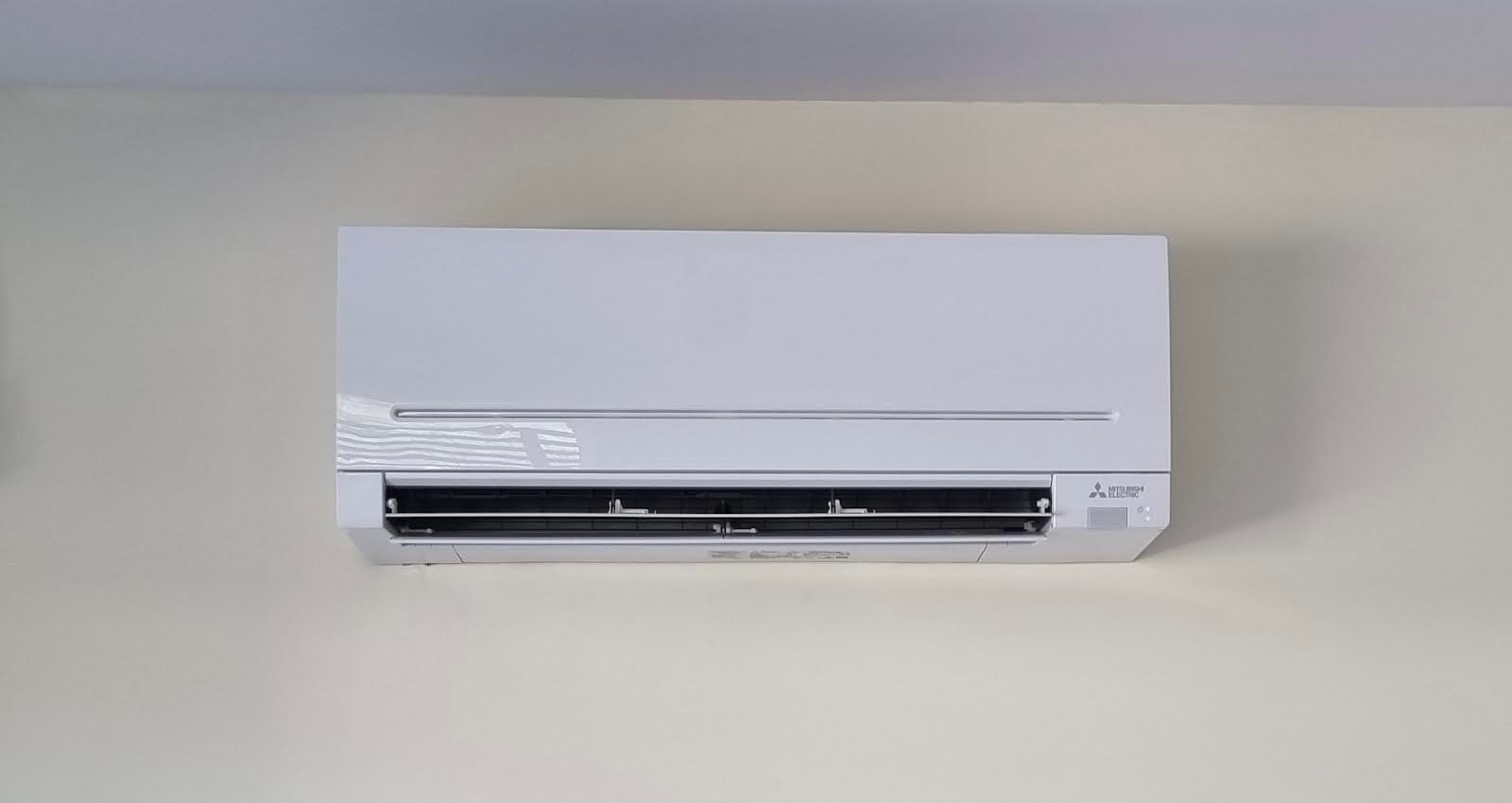 Biała jednostka wewnętrzna klimatyzacji Mitsubishi Electric zamontowana na jasnej ścianie w pomieszczeniu.